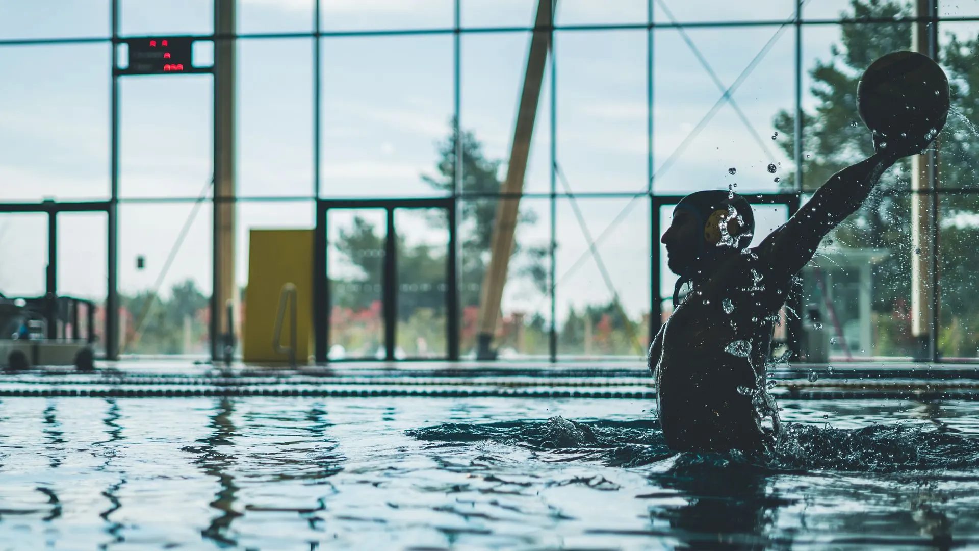 Wasserballspieler in einer Schwimmhalle, den Ball zum Wurf erhoben